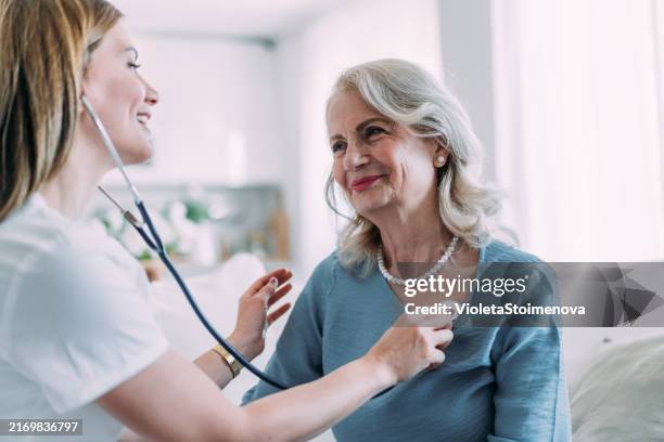 une infirmière vérifie les signes vitaux du patient. - auscultation au stéthoscope photos et images de collection