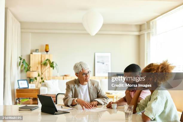 finance advisor explaining couple at apartment - plan financiero fotografías e imágenes de stock