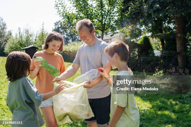 dad and his children clean up plastic waste in nature - climate action stock pictures, royalty-free photos & images