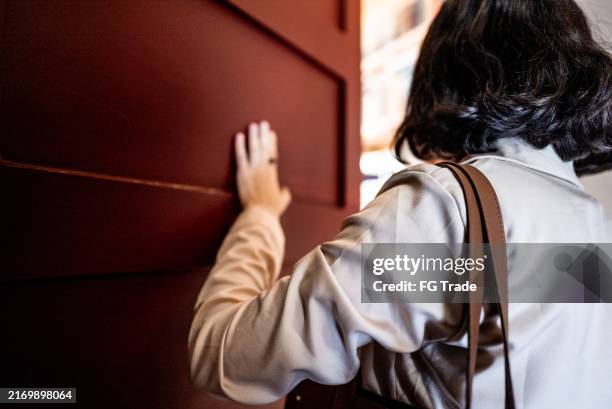 mature woman opening door at home - person-opening-door stock pictures, royalty-free photos & images
