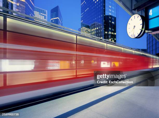 motion blurred train arriving at station in modern city at dusk - corsa contro il tempo foto e immagini stock