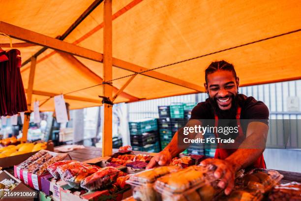 venditore che organizza la frutta in un mercato di strada - mercato di prodotti agricoli foto e immagini stock