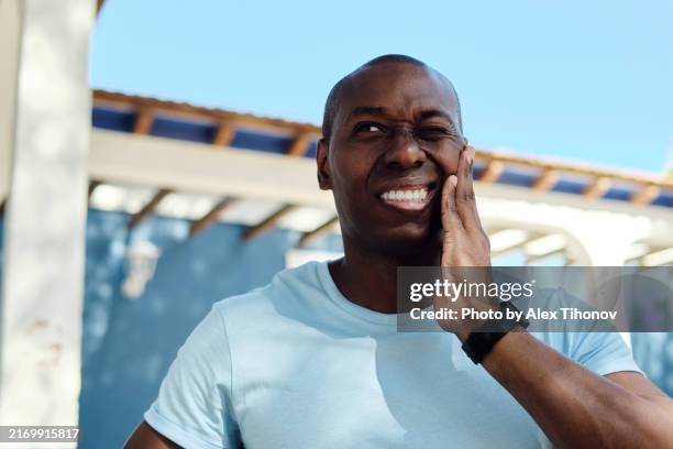 young 35s-40s man experiencing tooth pain outdoors. - menschlicher mund stock-fotos und bilder