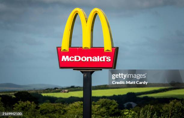 The sun shines on the yellow Golden Arches logo of the fast food restaurant McDonald's near Saint Austell, on August 14, 2024 in Cornwall, England....