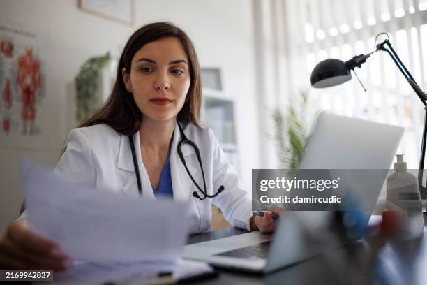 doctora trabajando en una computadora portátil en el consultorio - informe-médico fotografías e imágenes de stock