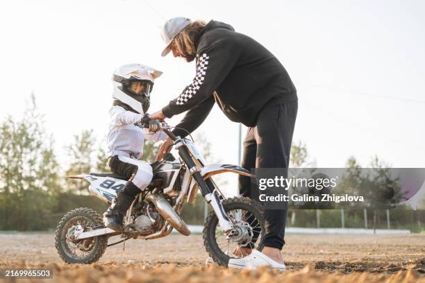 5-6 year old boy training for motocross with professional trainer - protective sportswear stock pictures, royalty-free photos & images
