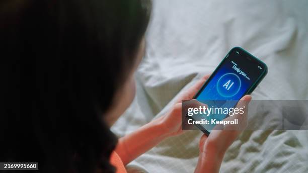 asiatische frau, die ki-apps im bett verwendet - chatbot stock-fotos und bilder