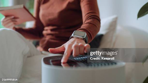 asian woman turn on air purifier - indoor air pollution stock pictures, royalty-free photos & images