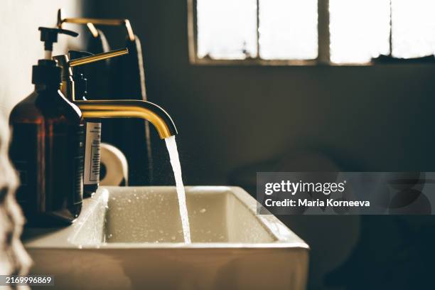 shot of an open tap with running water in a bathroom at home. - lavabo photos et images de collection