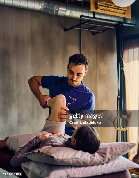 physiotherapist performing hip examination on patient. wide shot in rehabilitation clinic. healthcare and physical therapy concept. - physiotherapy stock pictures, royalty-free photos & images