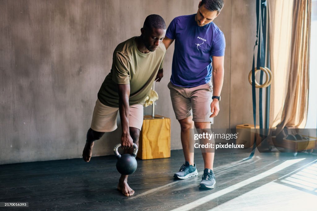 Physiotherapist guiding male patient through kettlebell exercise. Full-body shot in rehabilitation clinic. Healthcare and physical therapy concept