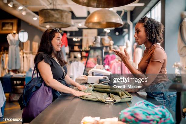 young saleswoman communicating with sign language with female customer standing at checkout counter in store - saleswoman stock pictures, royalty-free photos & images