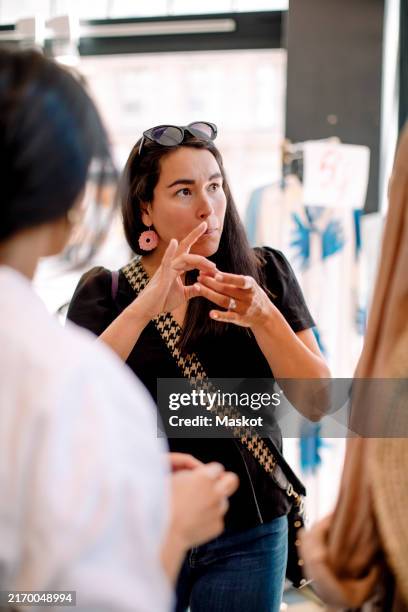 female customer using sign language while shopping at clothing store - deafness stock pictures, royalty-free photos & images