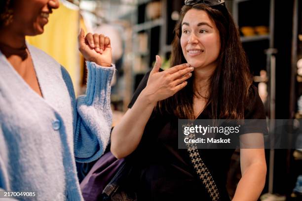 deaf female customer communicating with sign language with owner at clothing store - doofheid stockfoto's en -beelden