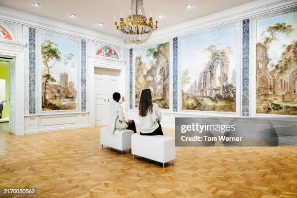 women admiring classical wall art in gallery - museum stock-fotos und bilder