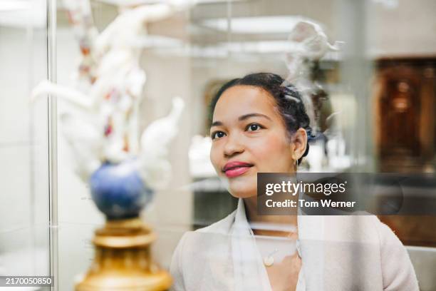 woman admiring porcelain art display - admiration photos et images de collection