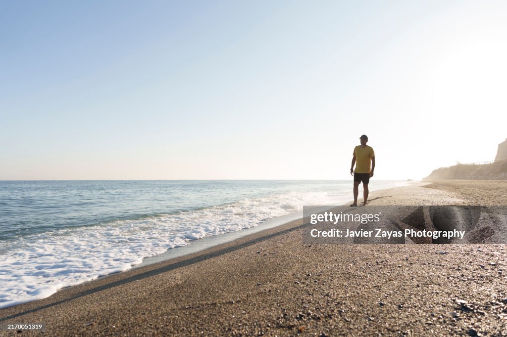 Middle aged Man Goes for a Walk on the Beach at Sunset
