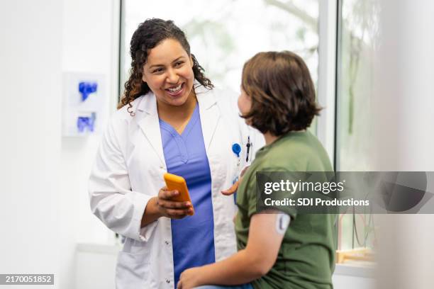 una doctora adulta sonríe mientras habla con su joven paciente - diabetes fotografías e imágenes de stock
