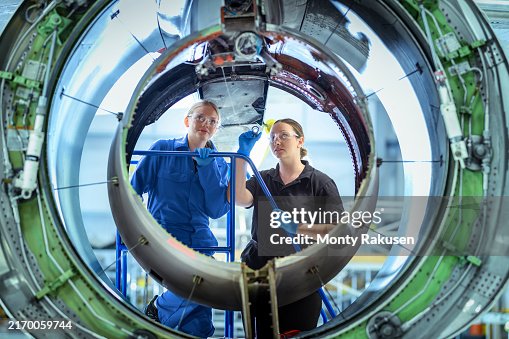 Engineering apprentice and instructor inspecting jet engine housing in aerospace training facility Engineering apprentice and instructor inspecting jet engine housing in aerospace training facility