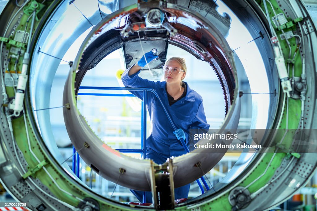 Engineering apprentice inspecting aircraft engine housing in aerospace training facility