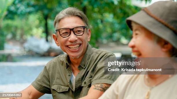 elderly asian man catching up with a group of old friends while meeting at a coffee shop. - southeast asian ethnicity stock pictures, royalty-free photos & images