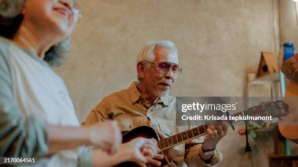 elderly asian friends playing music together at home on weekend. - plucking an instrument stock pictures, royalty-free photos & images