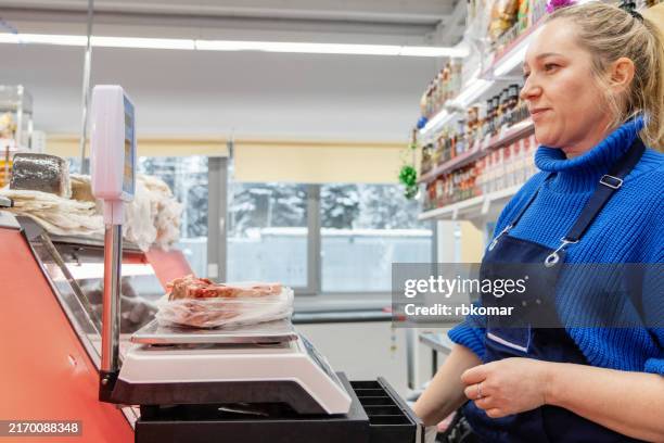retail worker weighing beef cuts at the grocery store counter - beef stock pictures, royalty-free photos & images