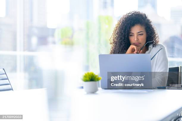 upset woman working on a laptop computer in the office. she looks worried - struggle stock pictures, royalty-free photos & images