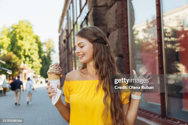 happy young woman in a dress holding an ice cream by a boutique on a street. - serviette stock-fotos und bilder