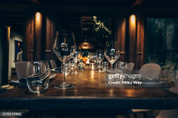 elegant table setting in fine dining room. beautifully set dining table with wine glasses in a dimly lit, upscale house. - dukning bildbanksfoton och bilder