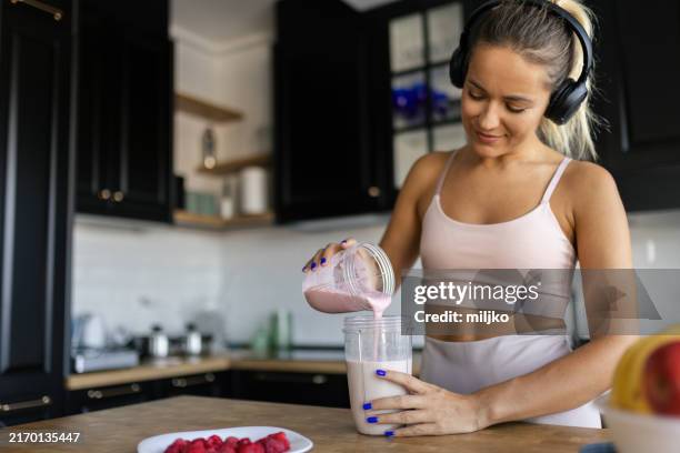 sportswoman preparing smoothie in her kitchen - smoothie bildbanksfoton och bilder