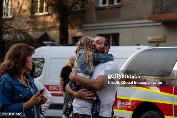 Man embraces with a child he holds in his arms at the site of a Russian missile strike on September 4, 2024 in Lviv, Ukraine. The Russian army...