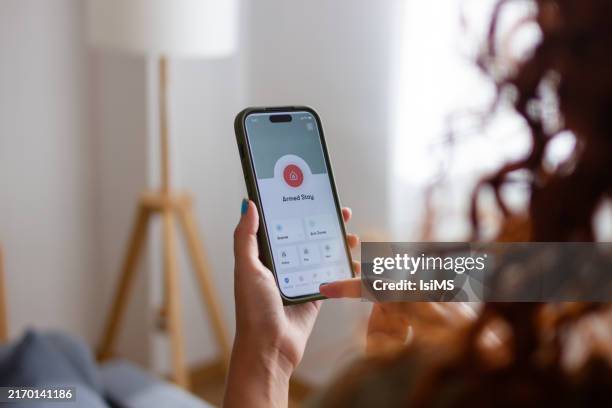woman arming home security system using smartphone app - styles stock pictures, royalty-free photos & images