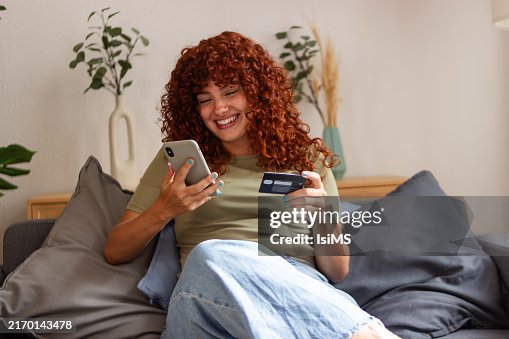 Femme heureuse utilisant smartphone et carte de crédit pour les achats en ligne sur le canapé à la maison Femme heureuse utilisant smartphone et carte de crédit pour les achats en ligne sur le canapé à la maison