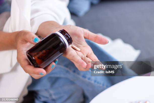 woman pouring pill from bottle into hand - folic acid stock pictures, royalty-free photos & images