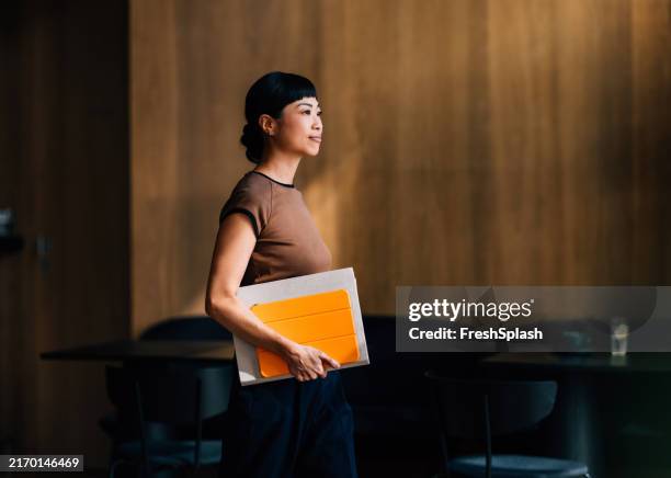 selbstbewusste frau, die notizbuch in moderner büroumgebung hält - business woman stock-fotos und bilder