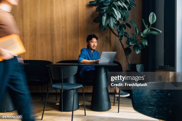 mann, der an laptop in modernem café mit holzinterieur arbeitet - coffee shop stock-fotos und bilder