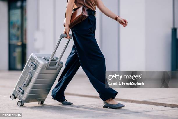 woman walking with suitcase on city street sidewalk - koffer stockfoto's en -beelden