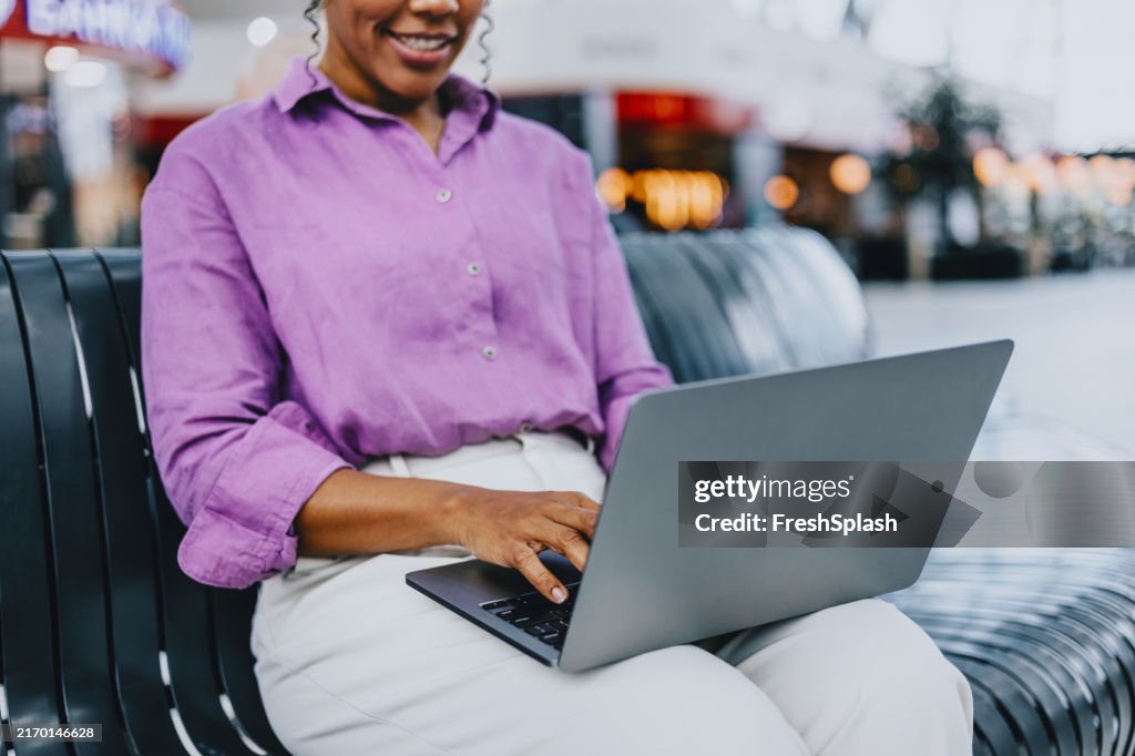 Woman Sitting on Bench Using Laptop in Shopping Mall