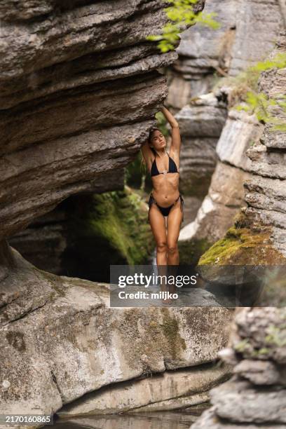 schöne frau, die auf einem felsen in einer bergschlucht steht - gebirgsbach stock-fotos und bilder