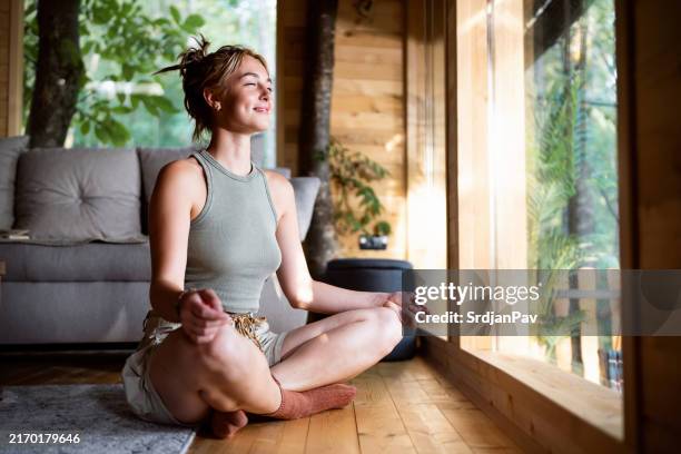 young caucasian woman mediating, from the tree house - budismo imagens e fotografias de stock