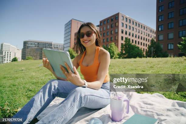 woman studying with a digital tablet in a sunny park - semester stock pictures, royalty-free photos & images