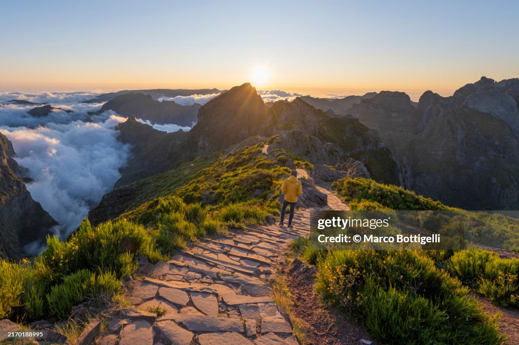 Man admiring sunset from pathway on mountain ridge