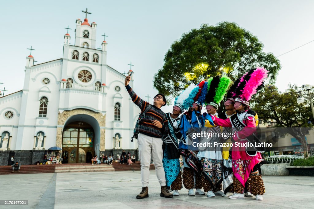 Tourist man taking a selfie or filming with shacshas dancer on Huaraz, in Peru