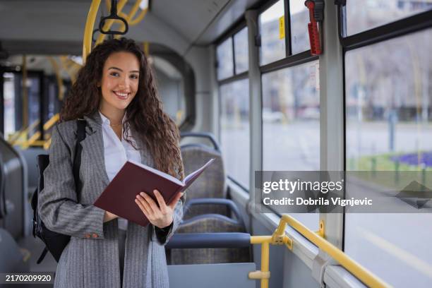 smiling girl studying during a bus ride - girl reading book on bus stock pictures, royalty-free photos & images