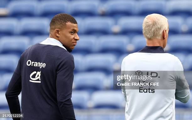 France's forward Kylian Mbappe speaks with France's head coach Didier Deschamps during a training session at the Groupama Stadium in...