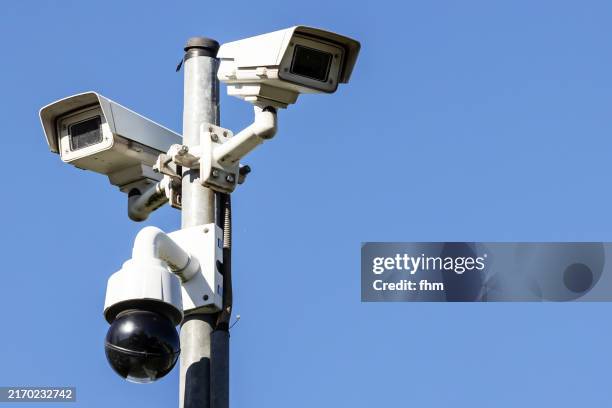 many surveillance cameras against blue sky - surveillance camera stock pictures, royalty-free photos & images