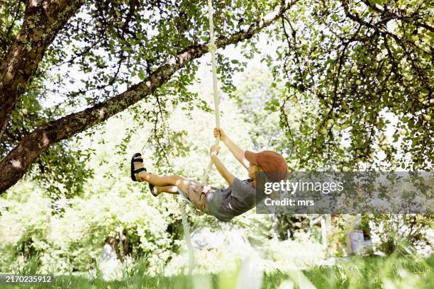 little boy swinging on rope swing - rope swing stock pictures, royalty-free photos & images