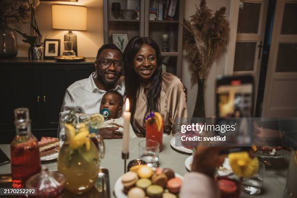 family dinner party - mom taking photos of baby eating imagens e fotografias de stock