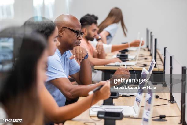 una mezcla de personas asisten juntas a una clase en un laboratorio de computación. - laboratorio de ordenadores fotografías e imágenes de stock